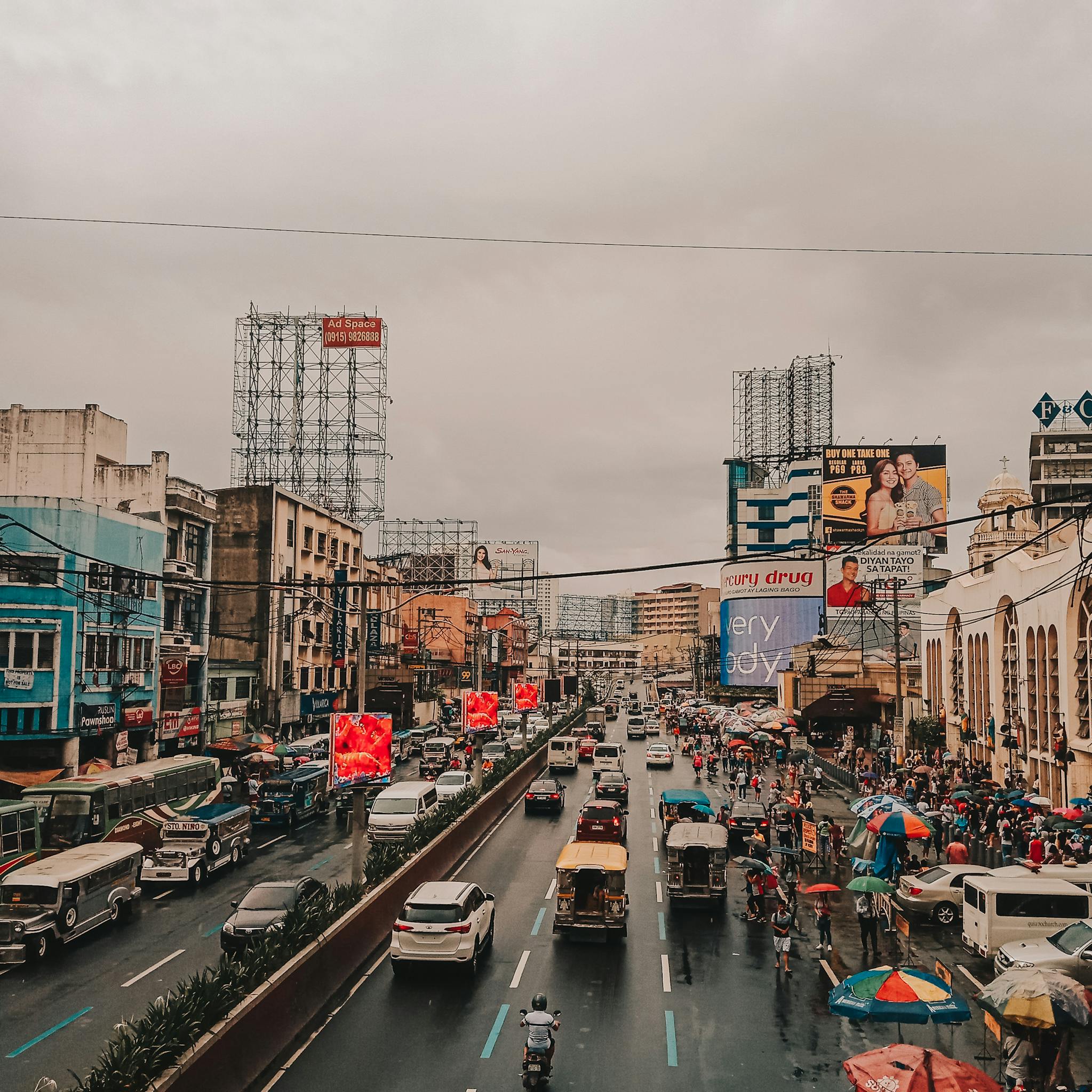 A bustling view of city life on a rainy day in Manila, showcasing traffic and bustling activity.